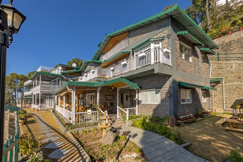 The villa exterior with stone walls, green roof and wraparound balconies